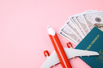 Indonesian Passport, Airplane And American Dollar Isolated On Pink Background with Copy Space