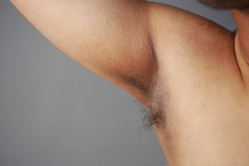 young man raised his hand up and showing his unshaven armpit 