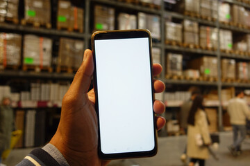 business owner holding phone mock up in warehouse.