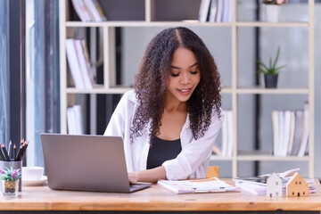 Businesswoman sitting at working desk in front of a laptop in the office.