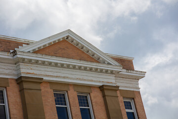Fototapeta premium old building with decorative beige brick cornice and triangle roof on cloudy sky