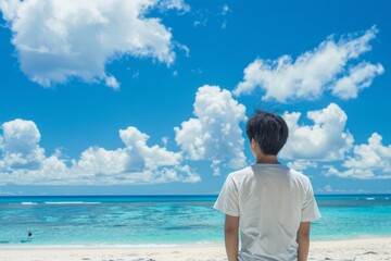 海を見ている日本人男性の後ろ姿（ビーチ・青空・旅行・休暇）