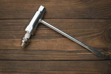 A short spark plug and a special key on a wooden background.