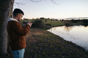 Photographer man taking photos of a lake at sunset