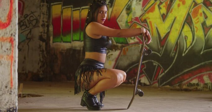 A skateboard-wielding young lady in a mini skirt making her way through an indoor skate park.