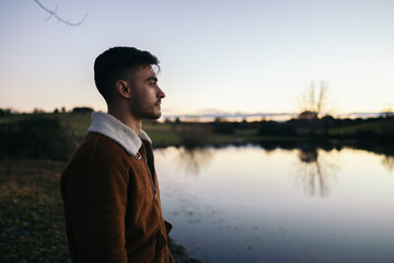 Young man watching the sunset at a lake in the countryside