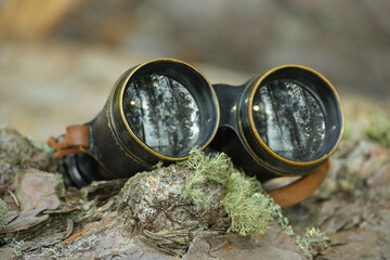 Aged binoculars with a leather strap resting in forest setting