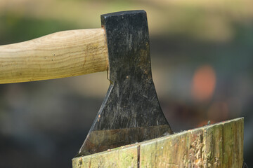 Closeup view of ax with wooden handle embedded in a log of wood