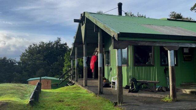 Green bunk house with clothes hanging to dry on partly cloudy day, New Zealand