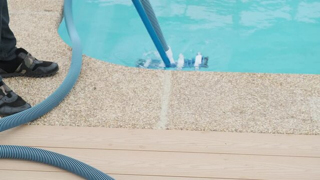 Male hand connects a hose to a mop to a vacuum cleaner to clean the water in the pool. Preparing and cleaning the pool for the swimming area
