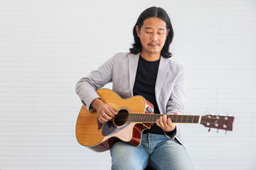 Asian artist singing song and playing acoustic guitar on white background for live acoustic concert and music related concept