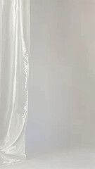 A white curtain hangs in front of a white wall