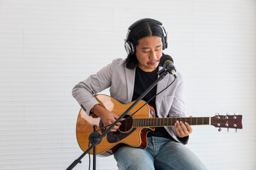 Asian artist singing song and playing acoustic guitar on white background for live acoustic concert...