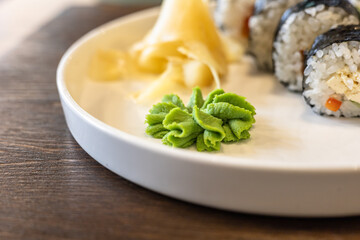 The green swirl of wasabi on your sushi plate close up. Wasabi, ginger, sushi on plate on wooden table