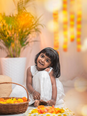 Happy Onam background, Cute little girl wearing traditional dress and making Onam pookalam with flowers