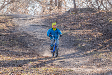 Obraz premium Little boy rides a bicycle in the autumn park.