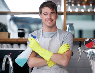 Crossed arms, spray bottle and portrait of man in kitchen with gloves for cleaning or housekeeping....