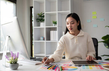Female designer working in graphic design on computer Sit and choose colors and work intently in your office.