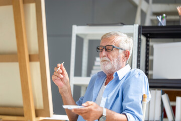 Elderly man painting on a canvas, Smiling mature man painting on canvas at home, Happy retirement concepts