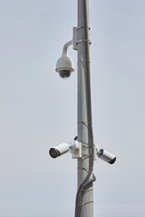 CCTV cameras are installed in the park on a power line pole, against the blue sky.