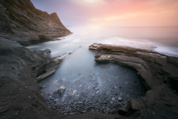 Tunelboka beach in Getxo, Bizkaia on a sunset with clouds and dramatic sky and with the sea beating the rocks of the coast