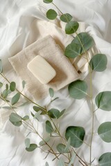 A white towel with a bar of soap on top of it. The towel is next to a green leaf