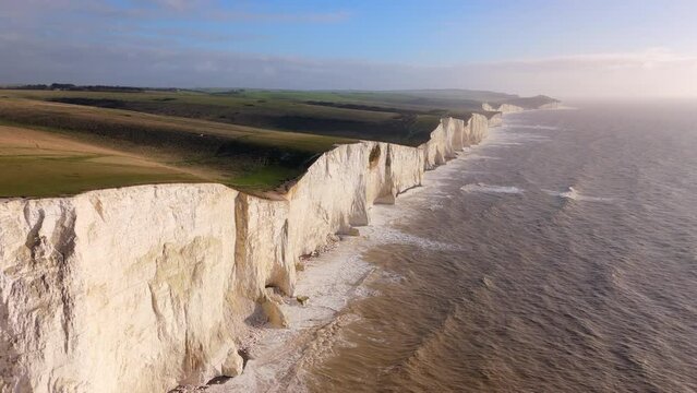 Towering white cliffs alongside the sea glow under the golden light of sunset, creating a breathtaking natural landscape symbolizing endurance and beauty. Seven Sisters, Brighton, United Kingdom 