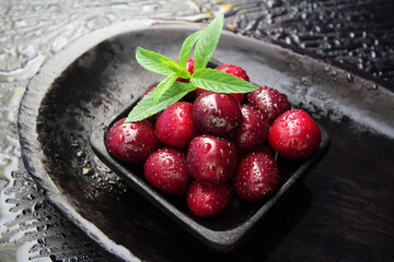 Cherries on a dark background in a square wooden plate. Ripe, large cherry berries are carefully...