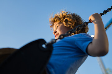 Kid swinging on swing in city park. Childhood, Freedom, Happy, Summer Outdoor. Cute child boy...