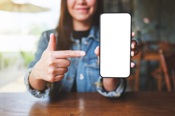 Mockup image of a woman holding, showing and pointing finger at a mobile phone with blank white...