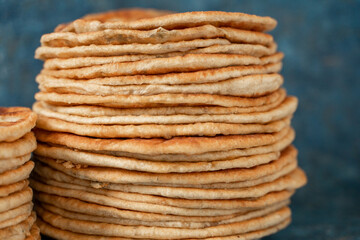 Flatbread lavash, chapati, naan, heap of tortilla on a blue background Homemade flatbread stacked.