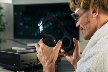 Male music meloman wearing headphones to listen to music on retro cassette boombox. In a room filled with memories, man enjoys music from a tape recorder