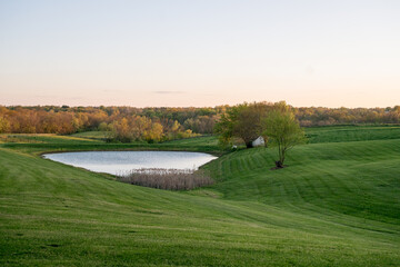 Landscape view of a farm with a pond at sunset