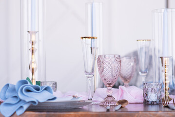 Elegant table decorated with pink goblets, flutes, and blue cand