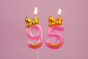 Pink birthday candle with bow and word happy burning on pink background., number 95.