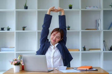 Asian businesswomen feel tired from hard work, thus doing arm stretching to relax the body. Tired...
