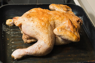 Pan of chicken is cooking on a stove. The chicken is cut and browned - Powered by Adobe