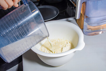 A child person is pouring milk into a bowl. The bowl is white