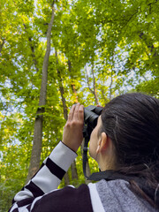 Birdwatching.  Vertical Photo with a woman filmed from behind while searching and scouting the...