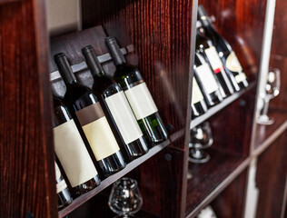 Fototapeta premium Bottles of wine displayed on the wine shelves in the restaurant or cafe close-up.