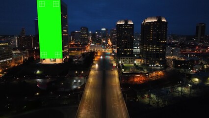 American city at night with green screen animated on skyscrapers for advertisement. Aerial of...