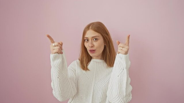Amazed young redhead woman in a cozy sweater looks up, pointing in surprise at an invisible lottery on a vibrant pink background. her eyes wide with joy, her confidence beams unabated.