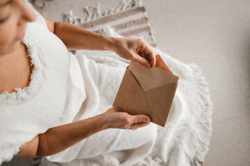 A woman in white clothes holds an envelope with a wish in her hands. The concept of a women's circle