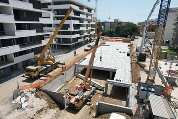 construction site with 2 crane trucks with operator taken to lift a large reinforced concrete beamdefault