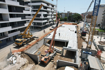 construction site with 2 crane trucks with operator taken to lift a large reinforced concrete...