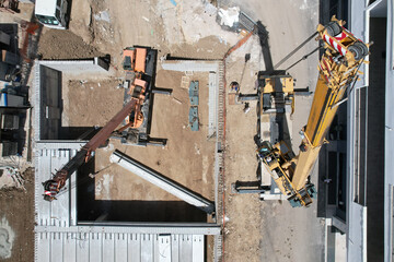 construction site with 2 crane trucks with operator taken to lift a large reinforced concrete...
