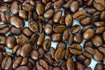 A pile of roasted coffee beans on a blue background.
