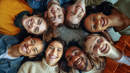 Group of people lying together in a circle looking up at the camera and smiling, Concept of friendship and unity,