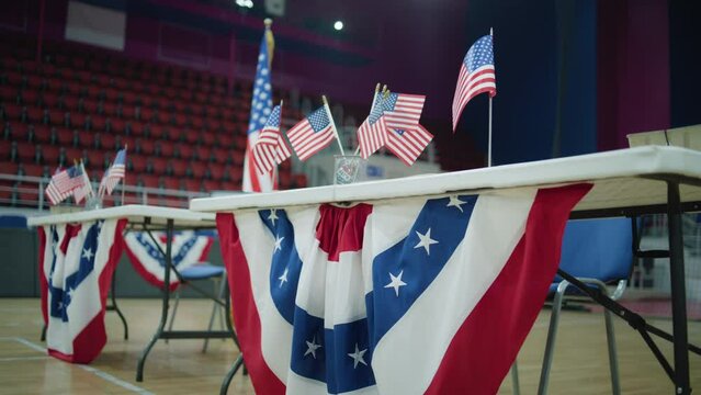 Table for voting registration with American flags stands at polling station. Elections in the United States of America. Presidential race and election coverage. Civic duty, patriotism and democracy.