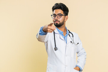 Hey you. Happy strict Indian young doctor cardiologist man pointing forward to camera, choosing,...